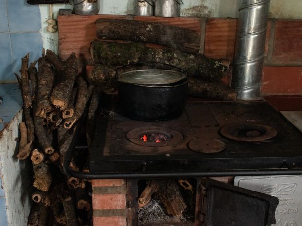 Con el calor de la estufa, uno de los beneficiarios seca los maderos fragmentados de un tronco de naranjo que se desplomó en su predio, ubicado en la cabecera del corregimiento San Vicente. Fotografía: Angie Serna Morales.